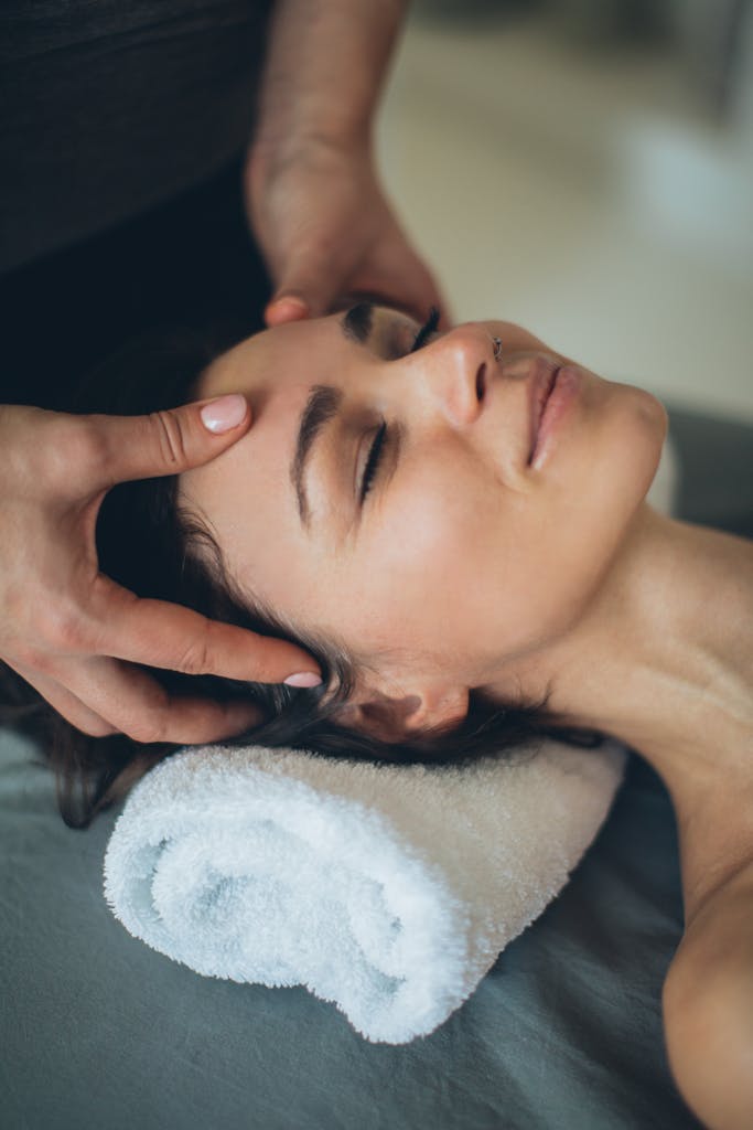 Woman enjoying a soothing facial massage at a spa, eyes closed and relaxed.